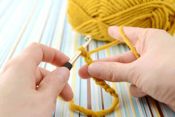 crocheting with brown wool in hand.