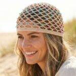 Mulher sorrindo usando headpiece de crochê bege com miçangas coloridas em ambiente de verão ensolarado