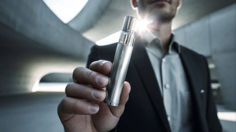 Homem com frasco de perfume de notas metálicas nas mãos