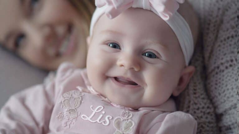 Bebê sorridente deitada com a sua mãe