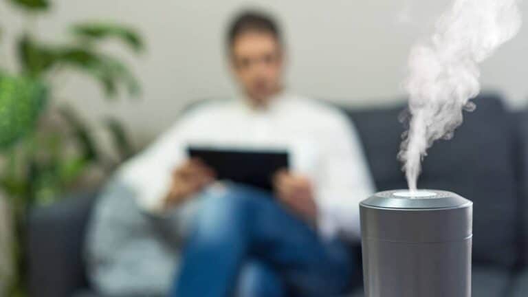 Difusor aromático em sala de estar com homem lendo livro ao fundo