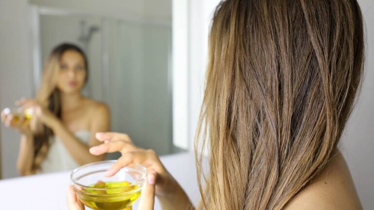 Mulher aplicando mistura com azeite no cabelo