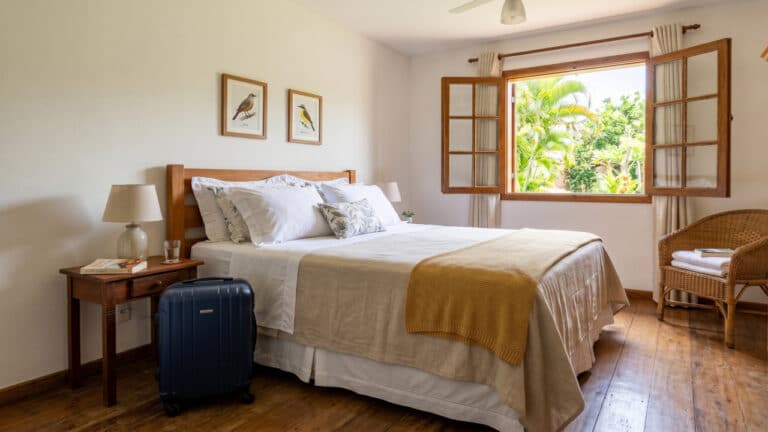 Quarto de hóspedes arrumado com mala ao lado da cama