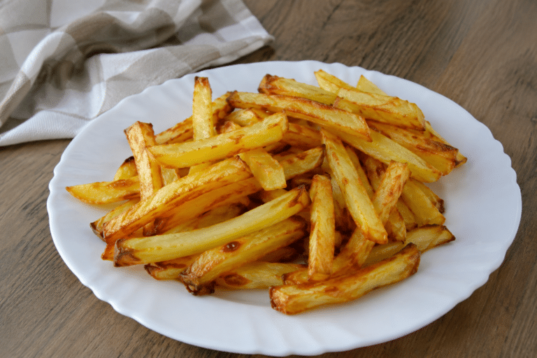 Prato com batata frita crocante preparada na air fryer servido em mesa de madeira