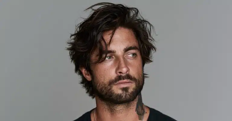 Homem com cabelo médio, volumoso e levemente ondulado, representando tendências de cortes masculinos para 2026.