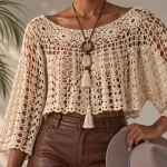 Blusa de crochê bege com pontos vazados, mangas amplas e estilo boho elegante.