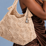Mulher usando bolsa de crochê bege com motivos geométricos e detalhes em tassel.
