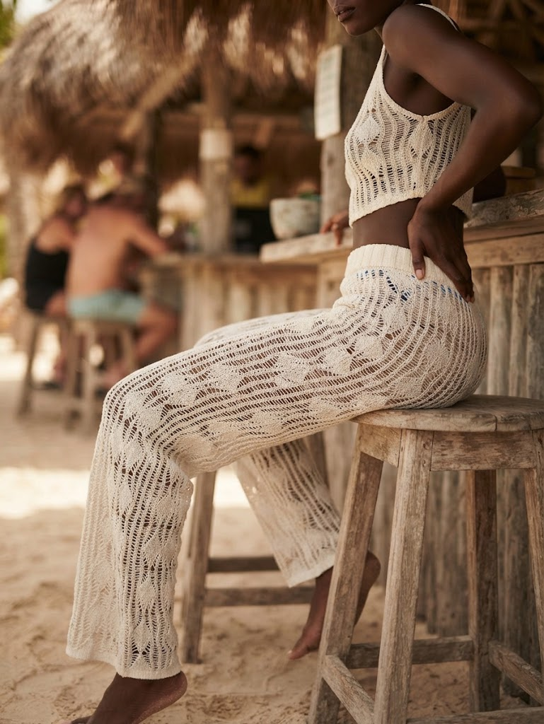 Calça de crochê branca com trama rendada e cintura alta em look sofisticado de moda praia.