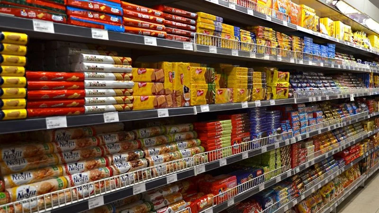 Prateleiras de supermercado repletas de biscoitos e bolachas de diferentes marcas e sabores.